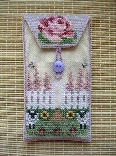 a cross stitch card holder with a pink rose on it and a button in the middle