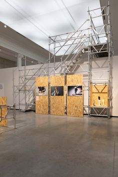 an empty room with scaffolding on the walls and pictures hanging on the wall