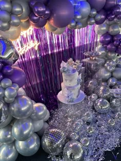 a table topped with a cake and lots of balloons