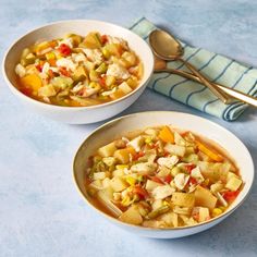 two bowls filled with soup sitting on top of a blue tablecloth next to a spoon