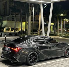 a black sports car parked in front of a building with palm trees and buildings behind it