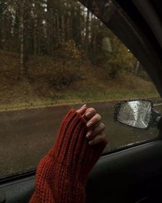 a person's hand on the dashboard of a car with trees in the background