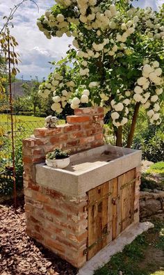 an outdoor kitchen made out of bricks with flowers growing on the outside and in front