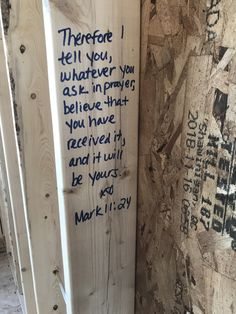 a wooden sign with writing on it next to a wall covered in wood planks