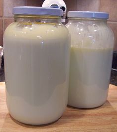 two glass jars sitting on top of a wooden cutting board next to a white dog