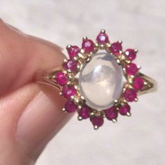 Stunning vintage cabochon moonstone ring bordered by sparkly faceted rubies. Here we have a silvery grey cabochon moonstone, with colour ranging from a dreamy pale grey to a lovely silvery grey. The sparkling brilliant cut rubies contrast especially well with the dreamy moonstone.  The moonstone is firmly claw set, as are the rubies, and are set in a solid gold 9ct band. The band is fully hallmarked for 9ct gold. The ring is in a good vintage condition, with minor age related wear. Measures:  Ring size:  UK. S 1/2.   US. A large 9 1/4                     Face of ring:  Width:  1.7cm.   x  Height:  1.8cm                     Moonstone:  0.8cm x 1cm                     Garnets:  0.2cm.  each                     Weight:  3.5 grams All weights and measures are approximate. Your lovely ring will Ruby And Moonstone Ring, Oval White Ruby Gemstone Ring, White Ruby Gemstone Ring, Ruby Gold Ring, Rose Gold Opal Ring, Lovely Ring, Lovely Shop, Multi Stone Ring, Moonstone Ring