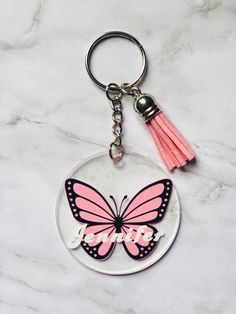 a keychain with a pink and black butterfly on it that says, girl