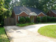 a red brick house in the middle of a yard with trees and bushes around it