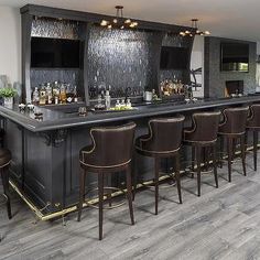 a bar with several chairs around it in a room that has wood floors and gray walls