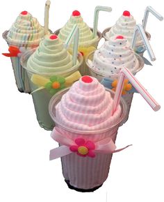 several cupcakes in plastic containers with straws and decorations on the top one