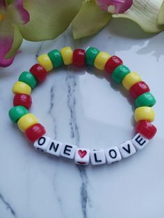 "Perfect for fans of Bob Marley, and just in time for the release of the biopic \"One Love\".  This is handmade at the time of order and is made using high-quality stretchy cord and beads. However, they are delicate, and I recommend you do not wear while sleeping, swimming, bathing, or working out.   One size fits most makes for easy gift giving. Standard bracelet size is 7 inches. If you need a custom size, please message me. Please measure your wrist before ordering. I am happy to do any size Friendship Beaded Bracelets With Letter Beads, Plastic Letter Beads Bracelets As Gift, Colorful Plastic Beads For Gifts, Plastic Stretch Bracelet With Round Beads For Gift, Plastic Stretch Bracelet With Round Beads As Gift, Handmade Themed Stretch Bracelet With Round Beads, Handmade Novelty Stretch Bracelet With Round Beads, Colorful Plastic Beaded Bracelets As Gift, Colorful Beaded Stretch Bracelet Perfect For Gifts