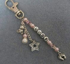 a key chain with charms attached to it on top of a gray table next to a cell phone