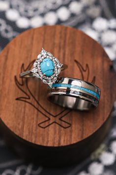 two wedding rings with turquoise stones are on a wooden stand