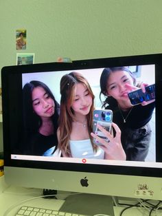 a computer monitor with two girls on the screen and a keyboard in front of it