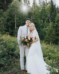 a bride and groom posing for a photo in front of the woods at their wedding