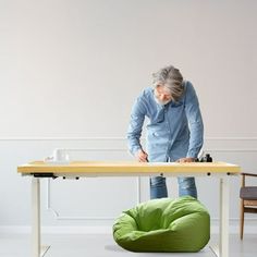 a person standing at a table with a green bean bag chair in front of it