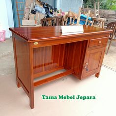 a wooden desk sitting on top of a floor next to a pile of boxes and chairs