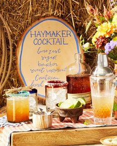 a table topped with bottles and glasses filled with drinks next to a sign that says haymaker cocktail