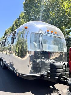 an airstream parked on the side of the road with trees in the back ground