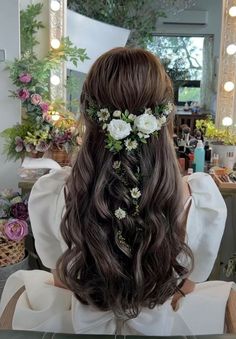 a woman sitting in front of a mirror with flowers on her head and hair comb