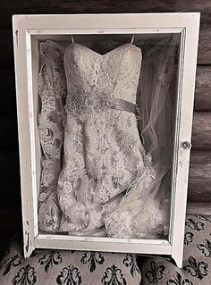 a wedding dress is in a box on a bed with a lace cover and veil