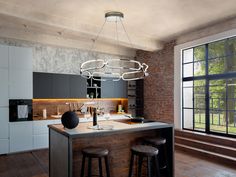 a kitchen island with stools next to it in front of a brick wall and windows