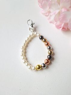 a bracelet with pearls and silver beads on it next to a pink peonie flower