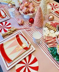 a table set for christmas with candy canes, cookies and cupcakes on it