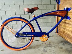 an orange and blue bicycle parked next to a brick wall