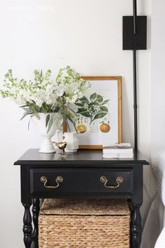 a black table with white flowers on it and a basket underneath the table next to it