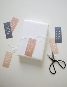 a gift wrapped in white paper and tied with twine, sitting next to some scissors