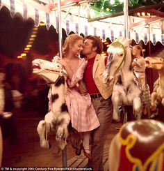 a man and woman are kissing on a merry go round