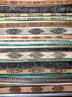 an assortment of different colored belts stacked on top of each other with intricate designs and patterns