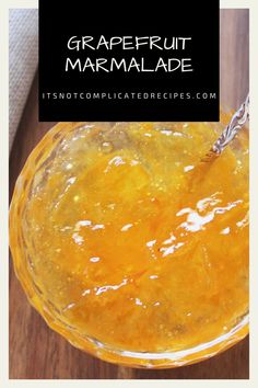 a glass bowl filled with orange marmalade sitting on top of a wooden table