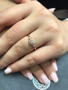 a woman's hand with pink and white manicured nails holding an engagement ring