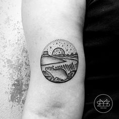 a black and white photo of a fish tattoo on the left inner arm, with mountains in the background