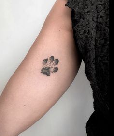 a woman's arm with a small tattoo of a dog paw print on it