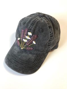 a gray hat with flowers embroidered on the front and side, sitting on a white surface