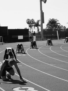 several people on a track with numbers painted on the ground and one person kneeling down