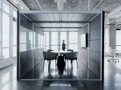 a person standing at a table in an open room with lots of windows and chairs