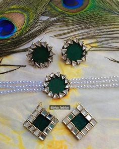 three pieces of green glass sitting on top of a white cloth next to a peacock's tail