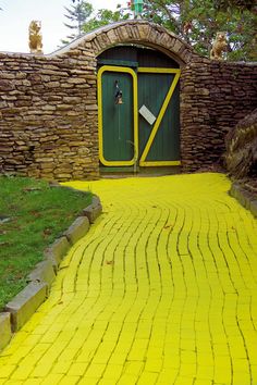 a yellow brick walkway leading to a green door