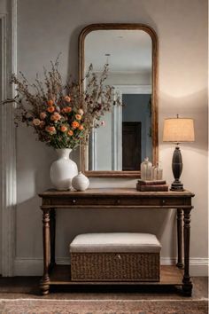 a vase with flowers on a table in front of a mirror and lamp next to a bench