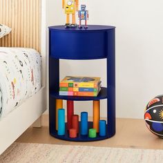 a blue shelf with toys on top of it next to a child's bed