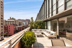 an apartment balcony with couches and tables overlooking the cityscape on a sunny day