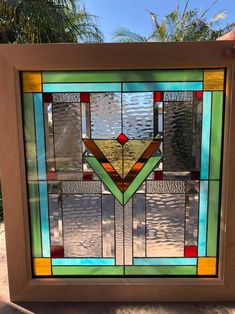 a colorful stained glass window sitting on the side of a building with palm trees in the background