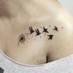 a woman's back with a dandelion tattoo on her left shoulder and two birds flying in the air