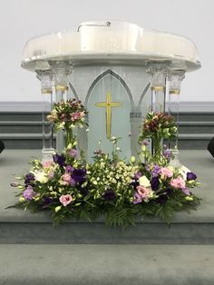 flowers and greenery are placed in front of the alter