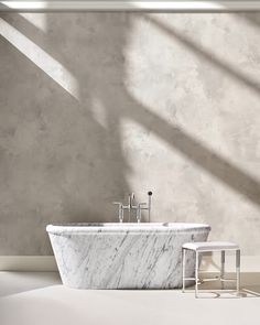 a bathroom with a marble bathtub and two faucets next to it on the floor