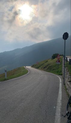 the sun shines brightly on an empty road with mountains in the backgroud